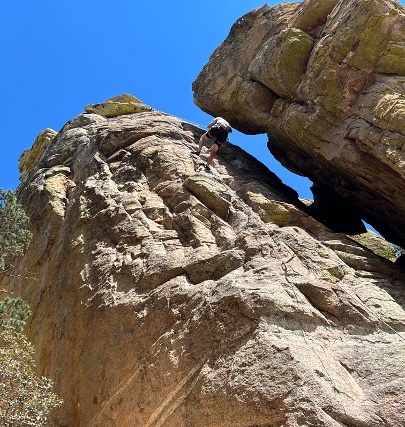 Compeditive Nature: Depicts a gentleman wearing sport attire rock climbing on a sunny day. 